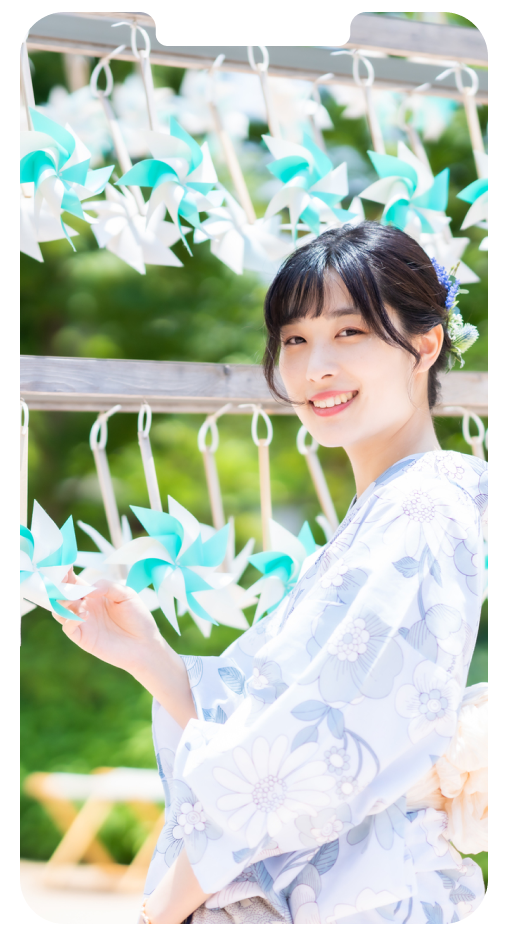 浴衣姿の女性が風車の前で微笑んでいる