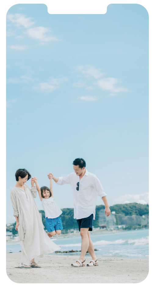 青い空と綺麗な海がある砂浜で親子三人手をつないで歩いている